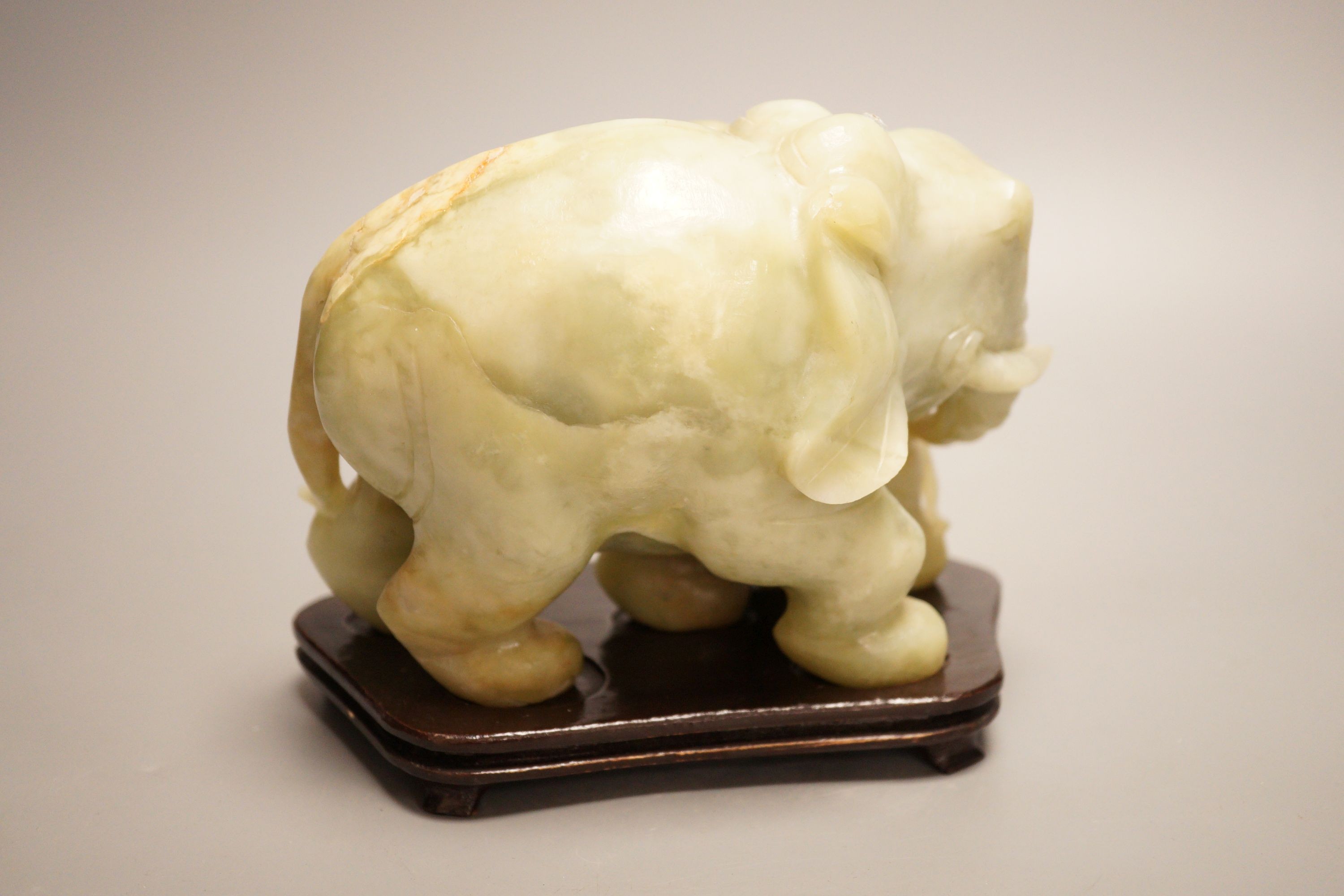A Chinese carved bowenite ‘elephant’ group on hardwood stand, 15cm